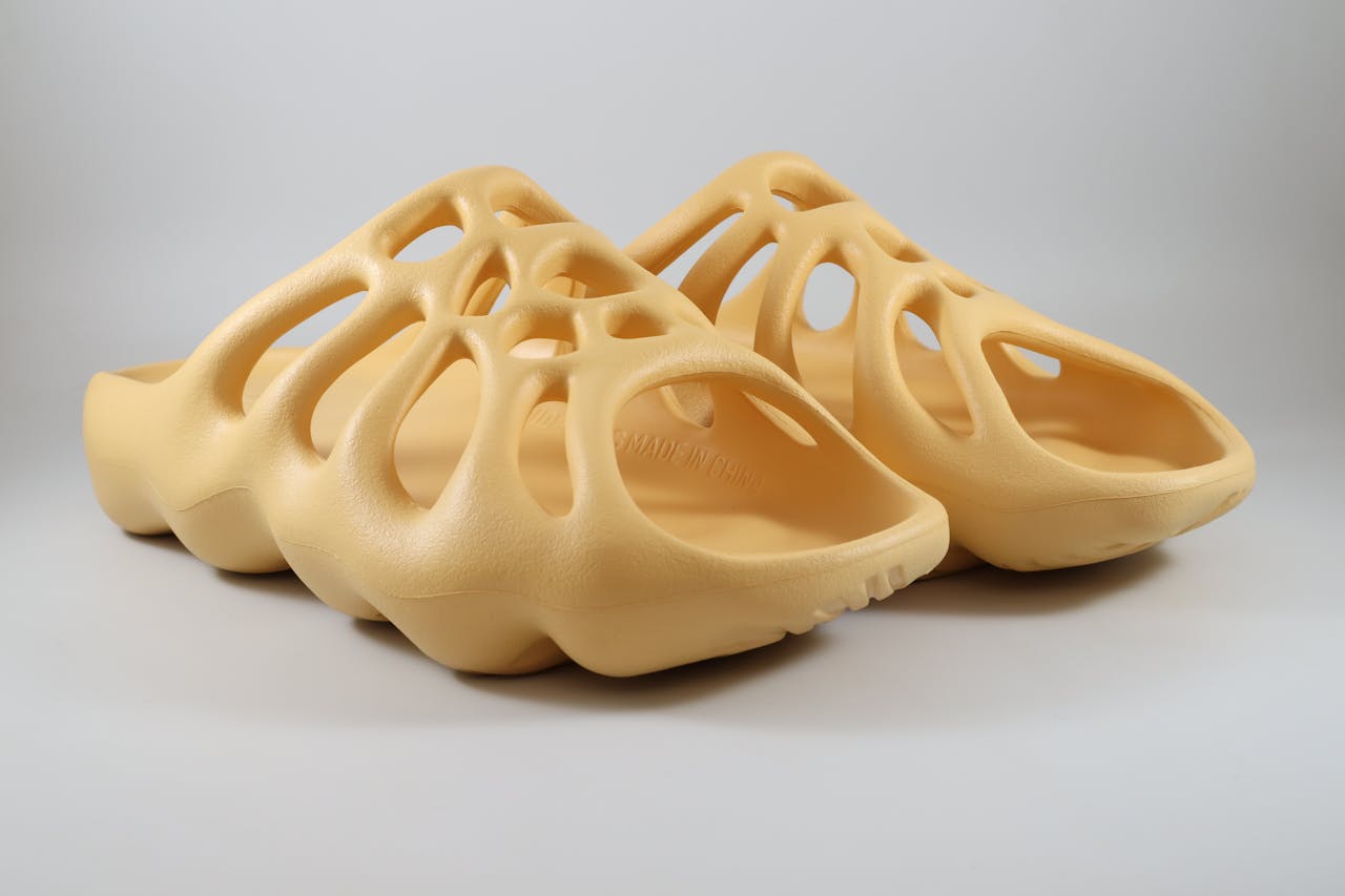 Beige slide sandals with a modern design on a white studio background.